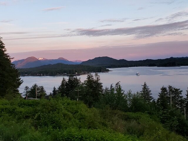 A distant shot of a lake surrounded by trees at sunset