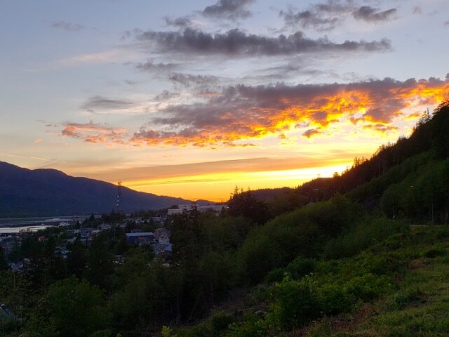 Sun beginning to rise and peek out from behind a mountain with homes on it