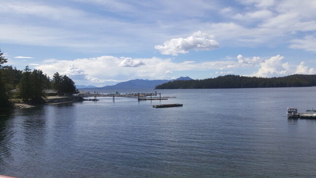 A dock out on a lake with a blue, slightly cloudy sky above it