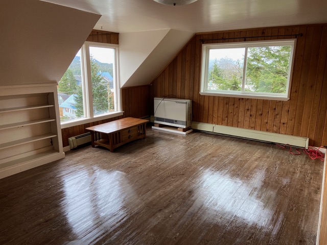 An empty room in a home with shiny, newly cleaned dark wooden floorboards and walls